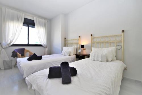 - une chambre avec 2 lits avec des draps blancs et des attaches noires dans l'établissement Estepona Port Apartment FLO, à Estepona