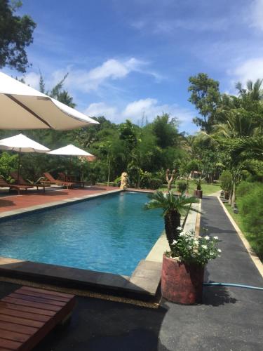a swimming pool in a resort with trees in the background at Red island villas in Banyuwangi