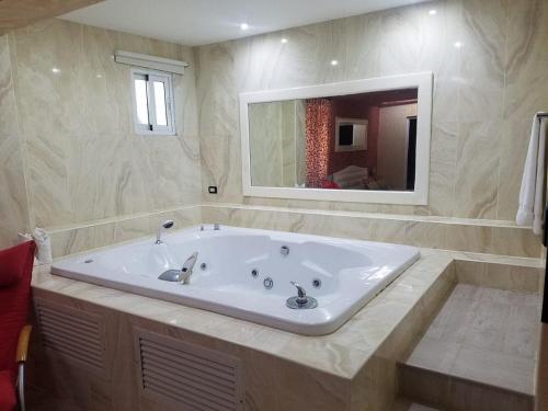 een groot wit bad in een badkamer met een spiegel bij Kitewind Apartamentos Cabarete in Cabarete