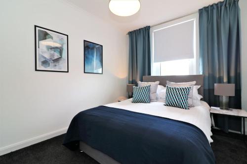 um quarto com uma cama grande e almofadas azuis e brancas em Macintosh Upper em Bellshill