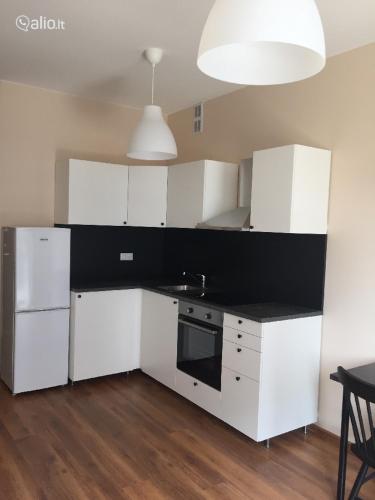 a kitchen with white cabinets and a black counter top at Near PANORAMA apartment Self check-in Garage free in Vilnius