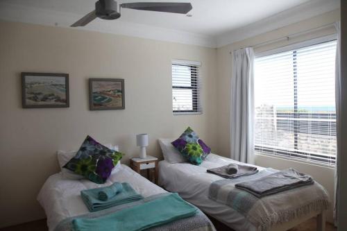 a bedroom with two twin beds and a window at Mossel is the Gem of Yzerfontein in Yzerfontein