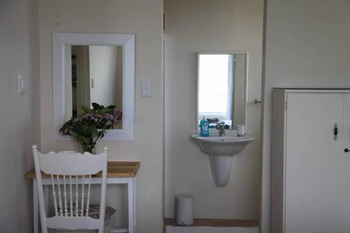 a bathroom with a sink and a mirror and a chair at Mossel is the Gem of Yzerfontein in Yzerfontein