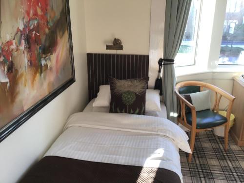 a small bedroom with a bed and a chair at Woodvale in Balloch