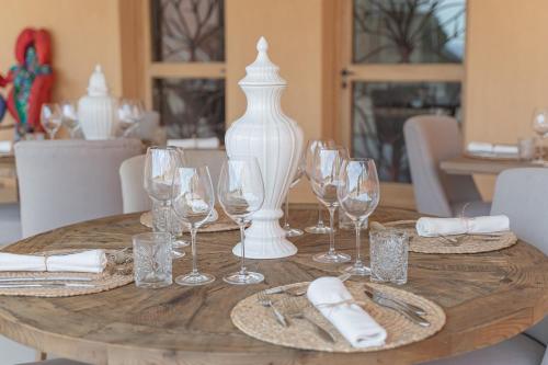 a wooden table with wine glasses and a vase on it at Borgo Smeraldo Villas in Arzachena