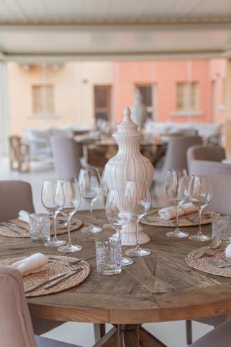 a wooden table with wine glasses and a vase on it at Borgo Smeraldo Villas in Arzachena