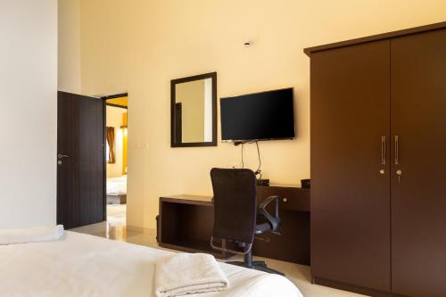 a bedroom with a desk with a chair and a television at Villa Knox in Benaulim