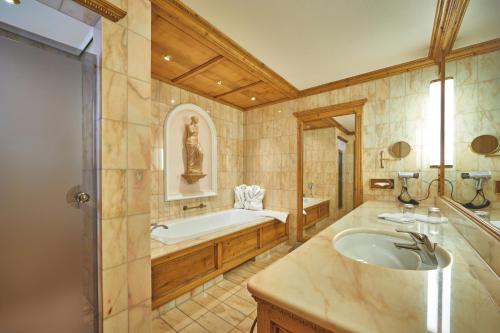 a large bathroom with a tub and a sink at Parkhotel Wallgau in Wallgau