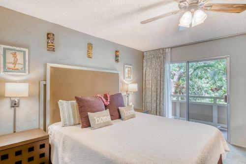 a bedroom with a bed with a ceiling fan and a window at Plantation Hale in Kapaa