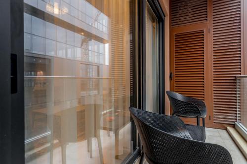 a balcony with two chairs and a table and a window at Athos Square Apartments in Podgorica