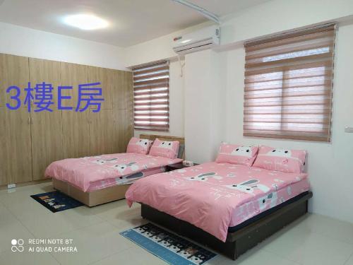 twee bedden in een kamer met roze lakens bij Soul Home in Jiaoxi