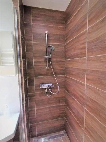 a shower with a shower head on a wooden wall at 2 Zimmer Apartment Hannover in Hannover