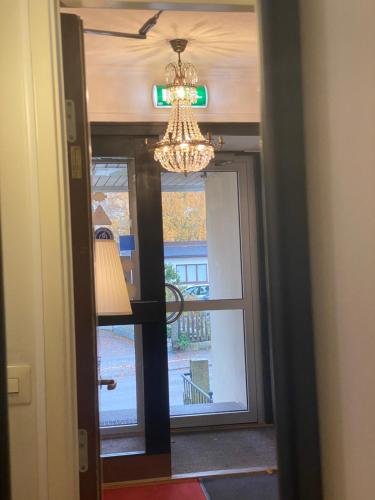 a hallway with a chandelier and a door with a window at Hotell Värend in Växjö
