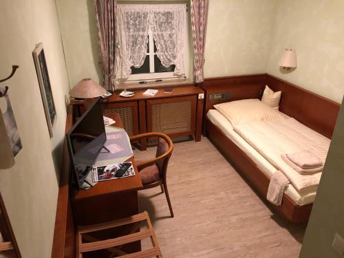 a small bedroom with a bed and a desk and a window at Akzent Hotel Gut Höing in Unna