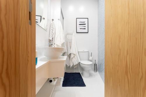 a white bathroom with a sink and a toilet at Casa da Porta Azul in Aveiro