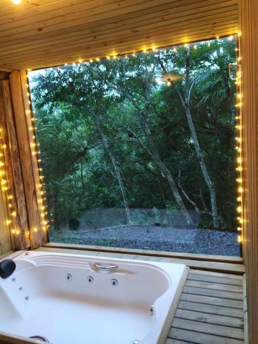 a bathroom with a window with lights around a tub at Cabana no Itaimbezinho in Praia Grande