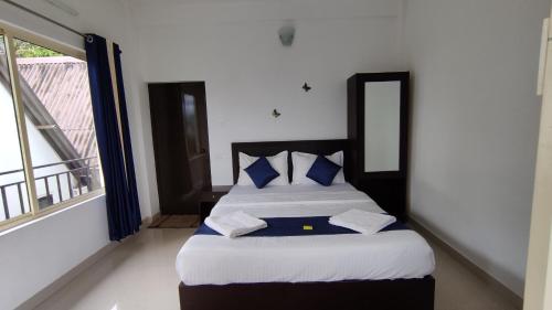 a bed with blue pillows in a room with a window at Green Tea View in Munnar