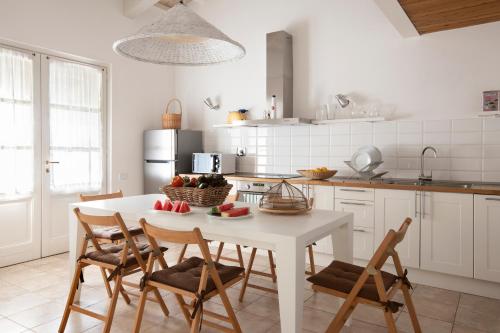 a white kitchen with a white table and chairs at Locanda Rossa in Capalbio