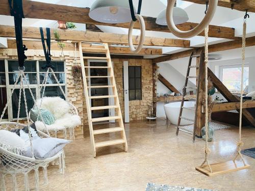 a room with a loft with a ladder and swings at Loft im Herzen der Stadt in Fürstenwalde