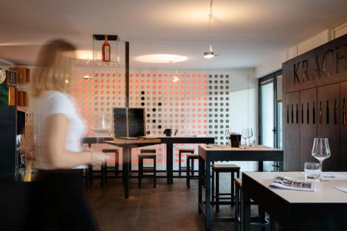 a woman standing in a restaurant with tables and chairs at KRACHER Guesthouse No 6 - inklusive Pool in Illmitz
