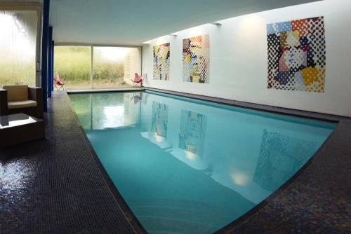 a large swimming pool in a house with paintings on the wall at La Petite Bruyere De Renaix in Ronse