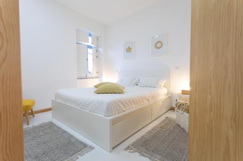 a white bedroom with a bed and a window at Casa da Porta Azul in Aveiro