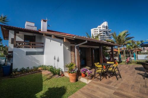 a small white house with a patio and a table at Pousada Vivenda da Barra in Torres