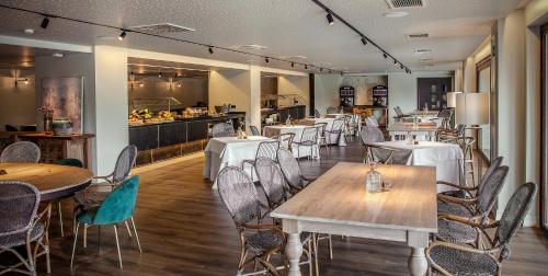 a restaurant with tables and chairs and a kitchen at Blanco Hotel Spa in Navia