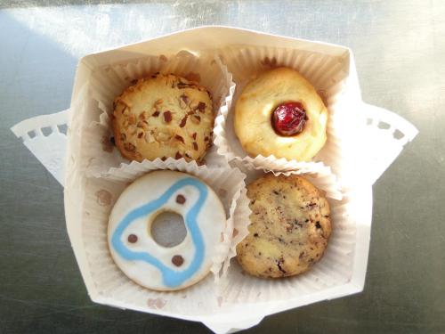 four donuts in a plastic container on a table at Hotel & Cafe Lanterna in Nauvo