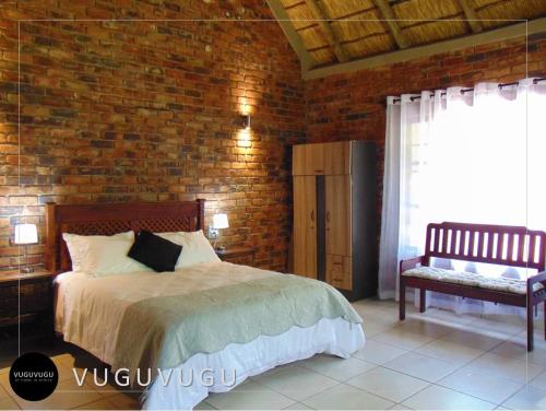a bedroom with a bed and a brick wall at VuguVugu - At home in Africa in Marloth Park