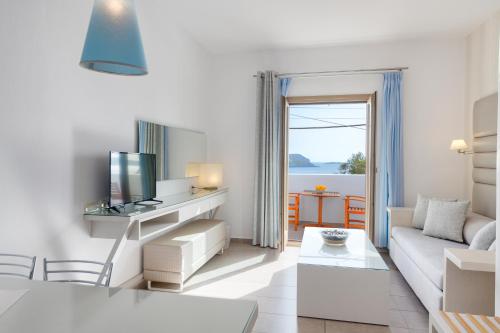 a white living room with a couch and a tv at Lithos by Spyros & Flora in Agios Ioannis Mykonos