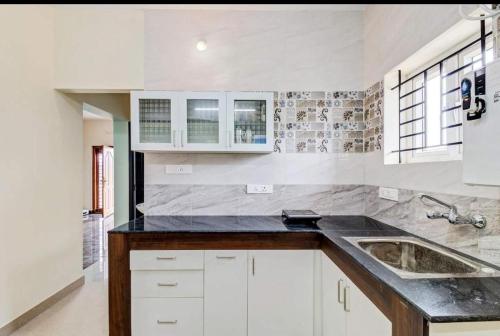 a kitchen with white cabinets and a sink at Brown Tree Resorts in Ooty