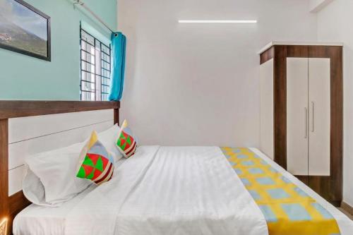 a bedroom with a white bed with pillows on it at Brown Tree Resorts in Ooty