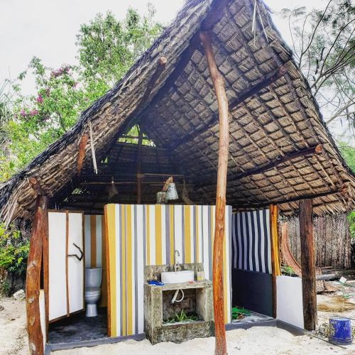 a small hut with a thatched roof and a sink at Michamvi Spirit Lodge in Michamvi