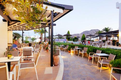 
a patio area with tables, chairs and umbrellas at Alianthos Garden in Plakias
