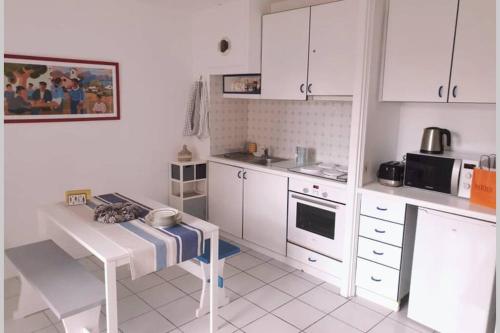 une cuisine avec des placards blancs et une table. dans l'établissement Itsas Aldea T2 à 3 min à pieds de la baie de St Jean de Luz, à Saint-Jean-de-Luz