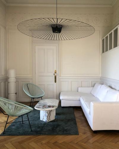a living room with a white couch and a chandelier at Magnifique Appartement dans palace Belle Époque in Aix-les-Bains
