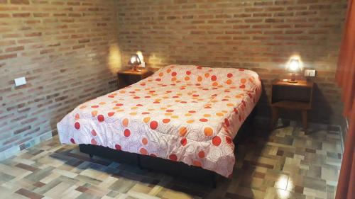 a bedroom with a bed and two tables with lamps at Luz Alba Cabañas in Mina Clavero