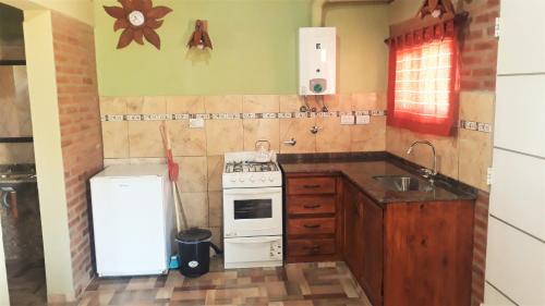 a small kitchen with a stove and a refrigerator at Luz Alba Cabañas in Mina Clavero