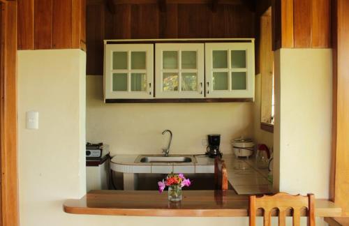 uma cozinha com armários brancos e uma mesa com flores em Casa Horizontes Corcovado em Drake