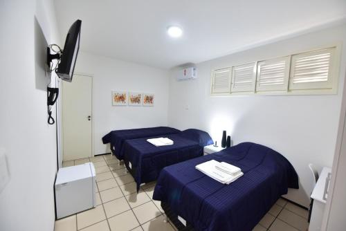 three beds in a room with blue sheets at LIVE IN FORTALEZA HOTEL in Fortaleza