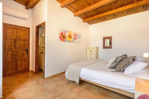 イビサ・タウンにあるShavasana Villaの白いベッドと木製の天井が備わるベッドルーム1室が備わります。