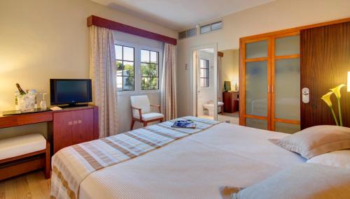 een slaapkamer met een groot bed en een televisie bij Hotel Patricia Menorca in Ciutadella