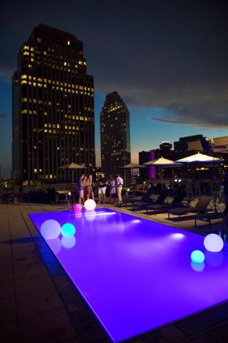 a rooftop pool with purple lights on a city skyline at NOPSI Hotel New Orleans in New Orleans
