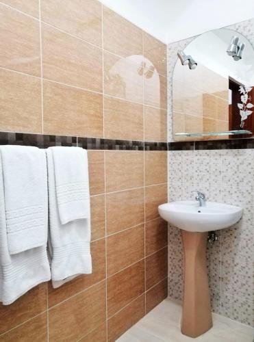 a bathroom with a sink and a mirror and towels at Hostel Boutique Marisol in Monte Gordo