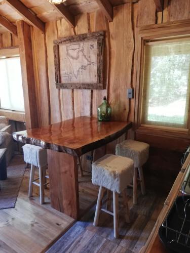 a dining room with a table and stools in a cabin at Cabaña Rústica Pellin in Pucón