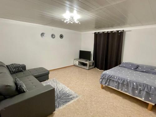 uma sala de estar com um sofá e uma cama em Appartement dans maison à Corbelin proche Walibi em Corbelin