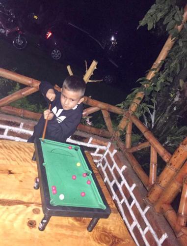 a young boy in a bow tie playing pool at CABAÑA LOS NOGALES in San Agustín