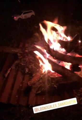 a fire in a grill with a car in the background at CABAÑA LOS NOGALES in San Agustín
