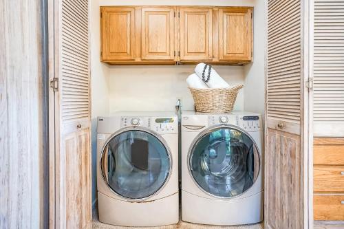 two washing machines in a laundry room with wooden cabinets at Sandcastles TVNC#1305 in Anahola